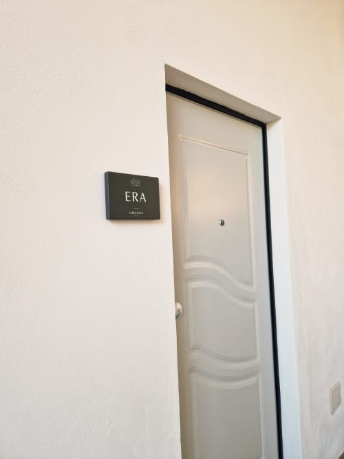 Porta bianca con pannelli ondulati con etichetta 'ERA' presso l'aparthotel Origenes Rooms a Procida, Italia