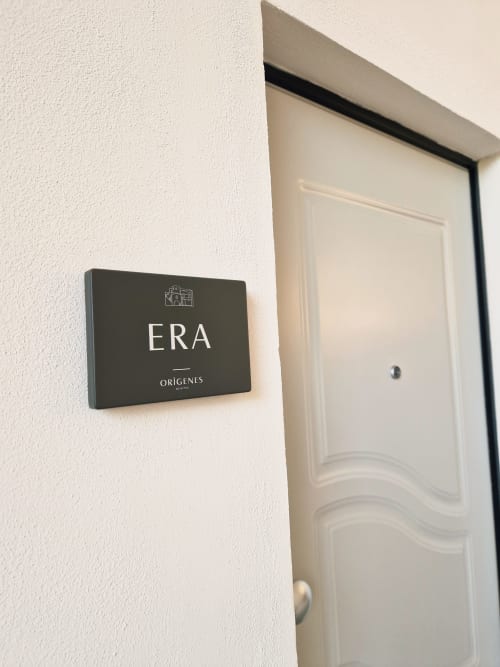 Ingresso della camera ERA presso Origenes Rooms, Procida - targa nera su parete bianca accanto a porta color crema