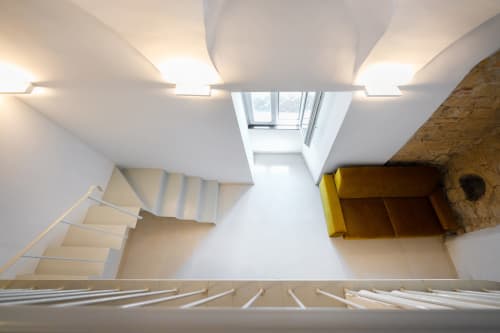 Interno moderno con soppalco, lucernario, scala, divano giallo e design minimalista presso Origenes Rooms, Procida