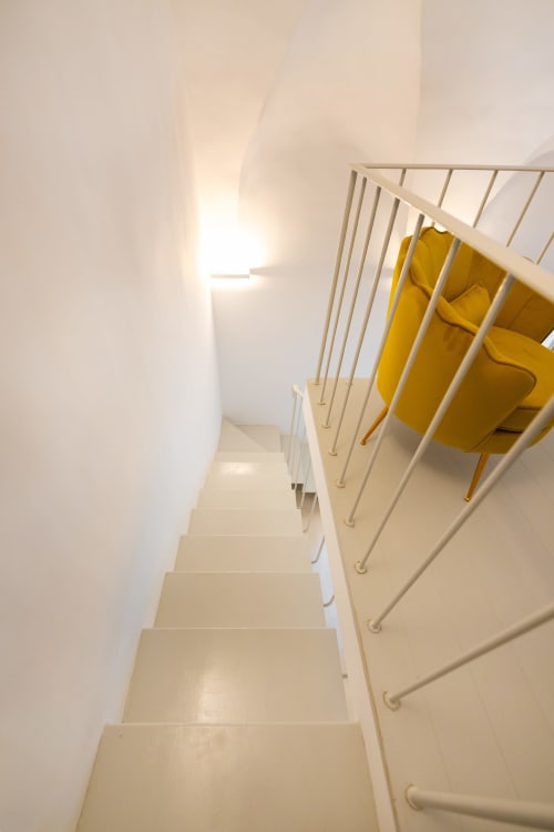 Scala moderna con ringhiere bianche e sedie gialle presso Origenes Rooms, Procida