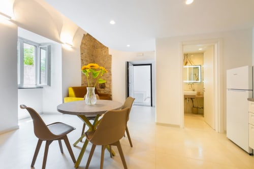 Cucina e zona pranzo moderna dell'Origenes Rooms a Procida con fiori gialli, tavolo rotondo e accesso alla vista mare