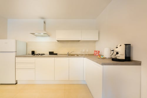 Cucina moderna nell'appartamento Era di Origenes Rooms, Procida con mobili color crema, top grigio e acciaio inox