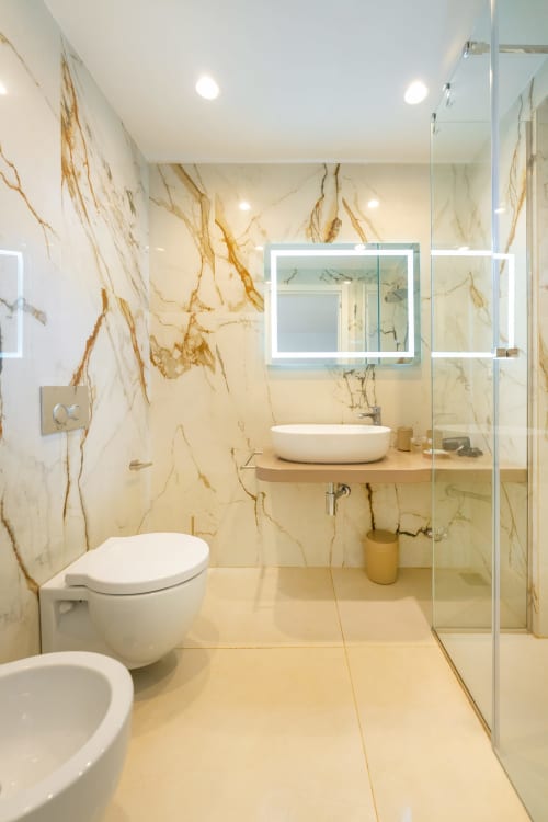 Lussuoso bagno in marmo dell'appartamento Era presso Origenes Rooms, Procida con lavabo design, specchio LED e doccia walk-in