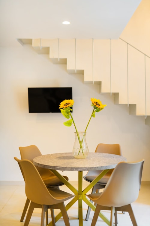 Moderna sala da pranzo presso Origenes Rooms, Procida con tavolo rotondo, sedie gialle e girasoli in vaso