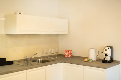 Angolo cottura moderno nell'appartamento Origenes Rooms con mobili color crema, piano in grigio, lavello, bollitore e caffettiera