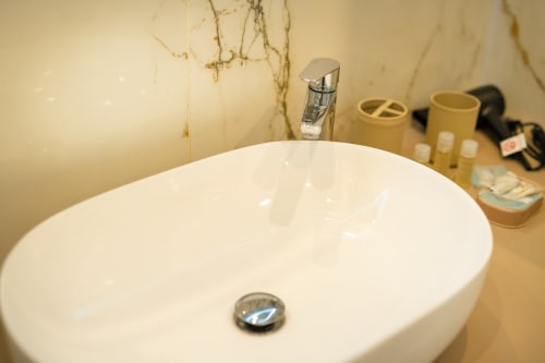 Lavabo rotondo bianco moderno con rubinetto cromato nel bagno dell'appartamento Era, Origenes Rooms, Procida