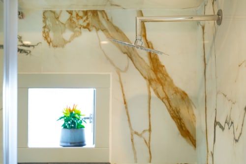 Bagno dell'appartamento Era presso Origenes Rooms, Procida, con doccia e pianta in vaso su ripiano