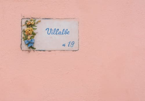 Villalbe room number sign with yellow flowers on pink wall at Origenes Rooms, Procida