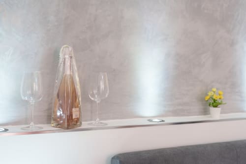 Wine bottle with glasses and yellow flowers on shelf at Origenes Rooms boutique hotel in Procida