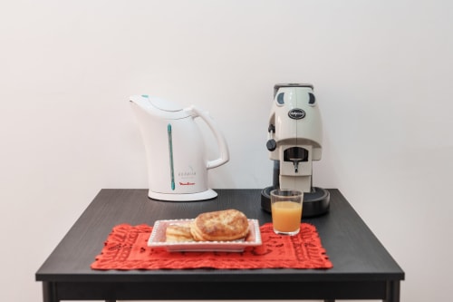 Coffee maker and electric kettle on dark table with pastry and juice at Origenes Rooms, Procida