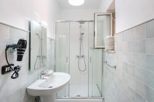Modern bathroom with glass shower enclosure at Origenes Rooms in Procida, Italy