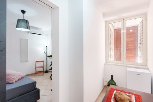 Modern bedroom at Origenes Rooms in Procida with bed, pendant lamp, orange chair, and window view