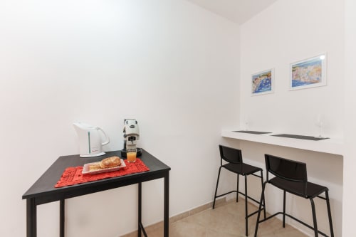 Kitchenette area at Origenes Rooms in Procida with kettle, coffee machine, and bar seating