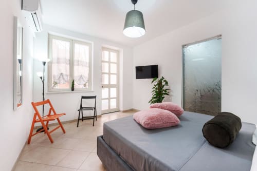 Spacious double bedroom at Origenes Rooms in Procida with bed, TV, AC, and modern furnishings