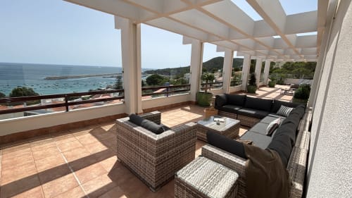 Panoramic penthouse terrace in Sesimbra with sea views, lounge seating, and pergola overlooking the Mediterranean coast.