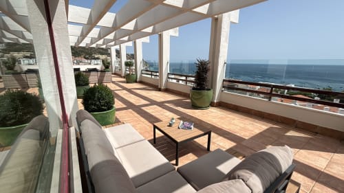 Panoramic penthouse terrace in Sesimbra with sea views, lounge seating, and pergola shade