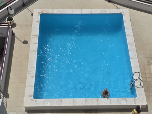 Overhead view of rectangular swimming pool with bright blue water at Sesimbra Sun Sea penthouse apartment, guest swimming