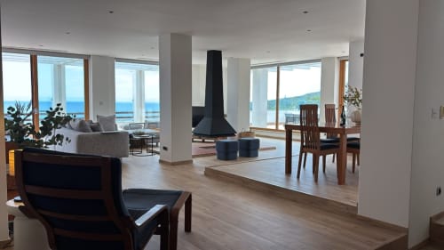 Spacious Sesimbra penthouse living room with panoramic sea views, modern fireplace, dining area, and floor-to-ceiling windows