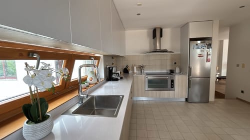 Modern kitchen in Sesimbra penthouse with stainless steel appliances, white countertops, and large windows with sea views