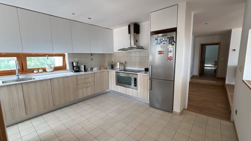 Modern kitchen in Sesimbra penthouse with wood cabinetry, stainless steel appliances, and sea view access