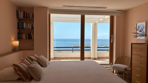 Spacious bedroom with sea view balcony overlooking Sesimbra coastline, modern furnishings and bookshelf