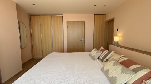 Modern bedroom in Sesimbra Sun Sea penthouse with queen bed, striped pillows, wooden doors, and warm lighting