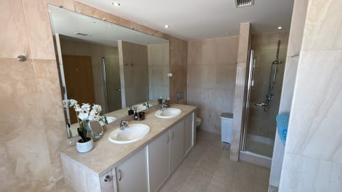 Modern bathroom in Sesimbra Sun Sea penthouse with dual sinks, large mirror, and shower enclosure
