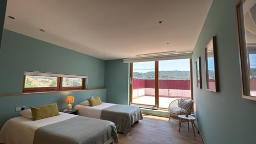 Bright twin bedroom with turquoise walls, sea views, balcony access, and wooden flooring in Sesimbra Sun Sea penthouse
