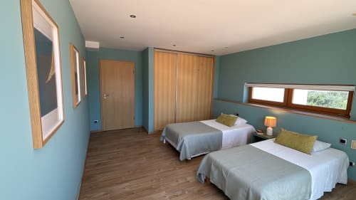 Spacious bedroom in Sesimbra Sun Sea penthouse with twin beds, turquoise walls, wooden furniture, and sea views through