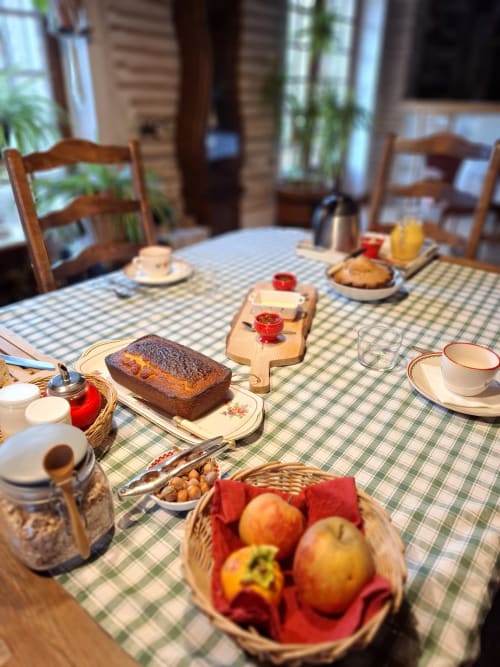 Breakfast table at Maison d'hôtes Les Gravets B&B with bread, fruit, coffee, and pastries in Sigalens, France
