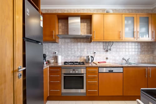 Cozinha moderna no apartamento DANI em RB Algarve Vilamoura com armários em madeira, eletrodomésticos em aço inoxidável e revestimento cerâmico