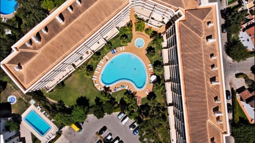 Vista aérea do hotel RB Algarve em Vilamoura com piscina em forma de rim, apartamentos, jardins e estacionamento