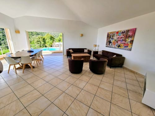 Modern living area in Villa Eva at Corsu Di Core with dining table, dark sofas, pool view, and contemporary decor