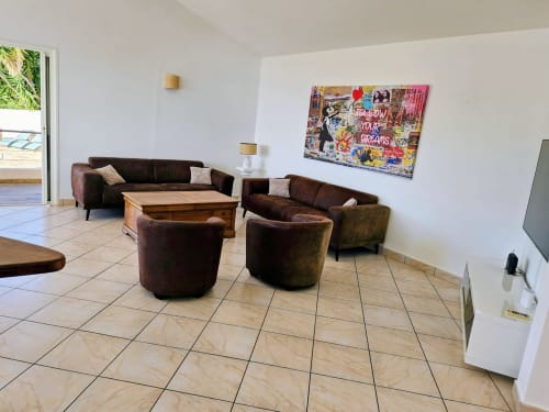 Modern living room in Villa Eva at Corsu Di Core, Favone, with dark brown leather seating, wooden table, and colorful artwork