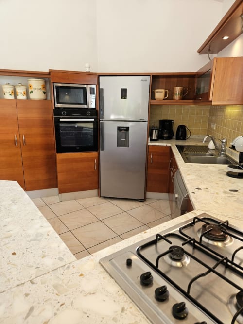 Modern equipped kitchen in Villa Eva at Corsu Di Core with gas cooktop, stainless fridge, oven, and marble counters
