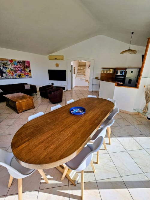 Modern dining area in Villa Eva at Corsu Di Core, Favone, with wooden oval table, white chairs, and open-plan living space