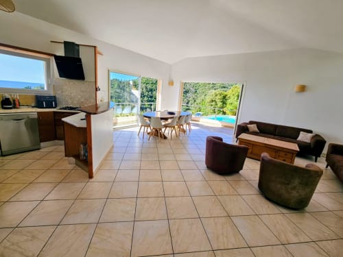 Villa Eva open-plan living room with kitchen, dining area, and lounge overlooking sea view, Corsu Di Core, Favone
