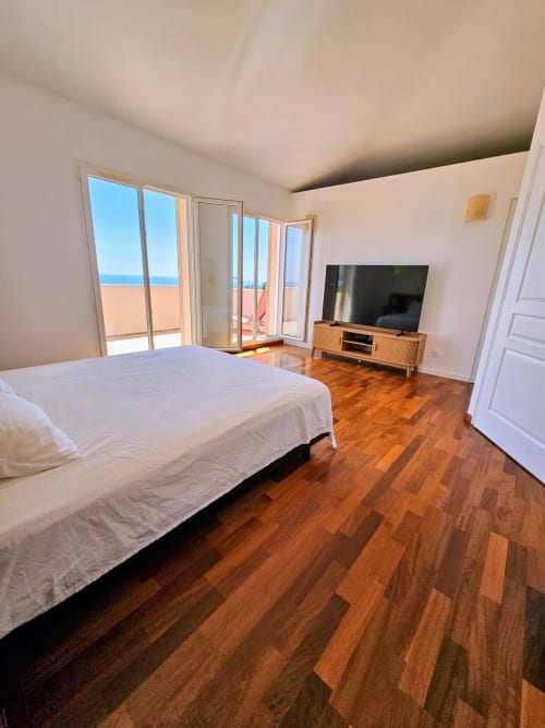 Spacious bedroom in Villa Eva at Corsu Di Core with sea view, wooden floors, bed, TV, and beachfront balcony access