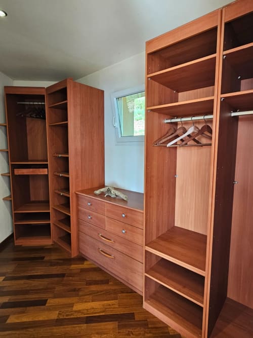 Spacious wooden wardrobe closet with hanging space, drawers, and shelving in Villa Eva at Corsu Di Core, Favone