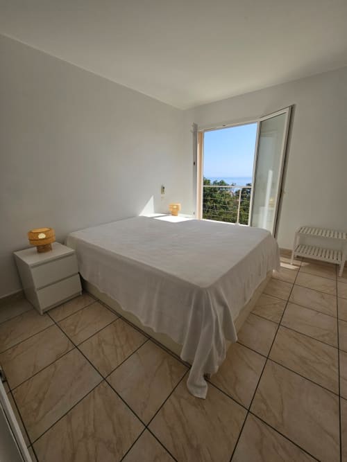 Bright bedroom in Villa Eva at Corsu Di Core, Favone, with sea view through sliding glass doors and modern furnishings
