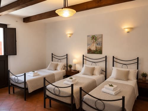 Camera quadrupla Borgo Luce con tre letti singoli, strutture in legno scuro, biancheria beige e travi rustiche a Francavilla