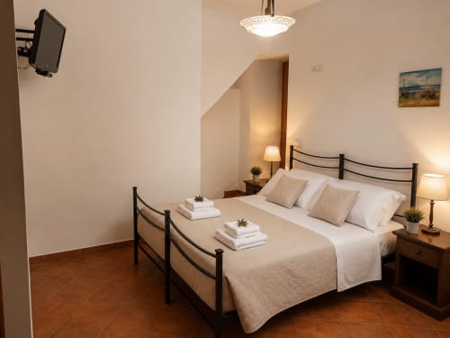 Camera matrimoniale al piano terra di Borgo Luce a Francavilla Marittima con letto in ferro battuto, pavimenti in cotto e arredi moderni