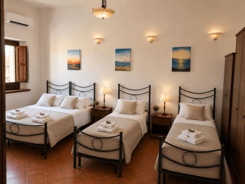 Camera quadrupla al Borgo Luce B&B di Francavilla Marittima con tre letti, opere d'arte costiera e illuminazione calda