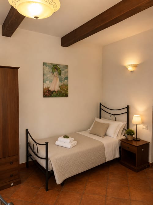 Camera accogliente al Borgo Luce B&B di Francavilla Marittima con letto in ferro battuto, travi in legno e illuminazione calda
