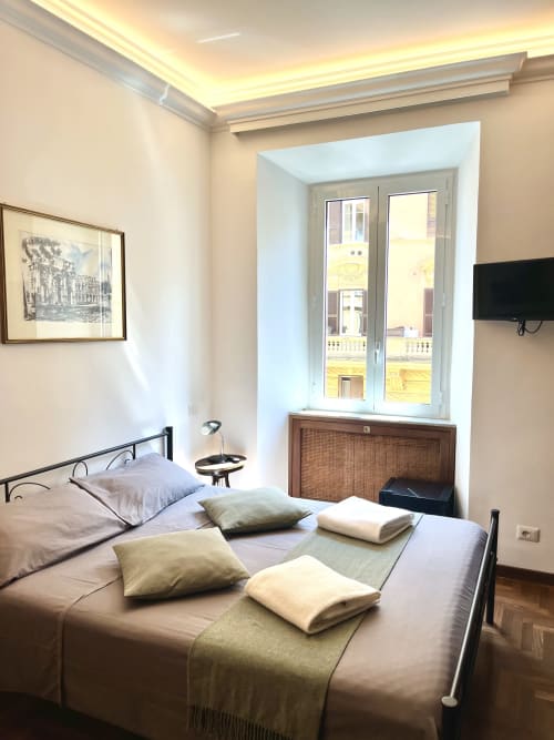 Camera luminosa a Domus Giovanna Roma B&B con letto matrimoniale, finestre con vista su monumenti, TV e quadri incorniciati