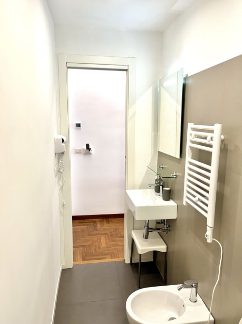 Bagno moderno a Domus Giovanna Roma con lavabo bianco, scaldasalviette e vista sui monumenti della città