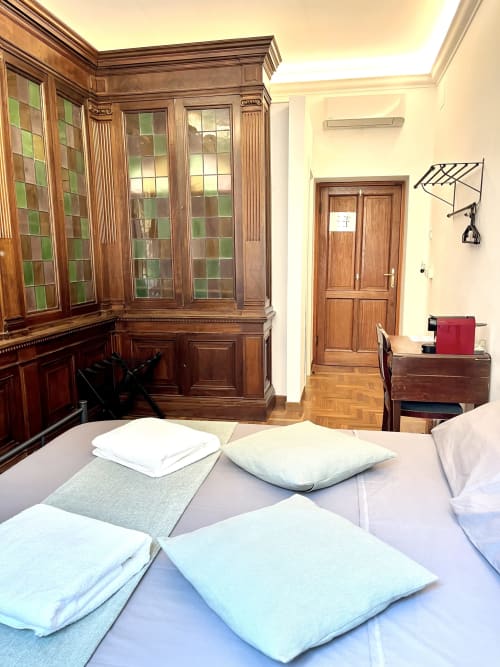 Elegante camera da letto in biblioteca presso Domus Giovanna B&B a Roma con mobili antichi in legno, cuscini bianchi e pavimento in parquet