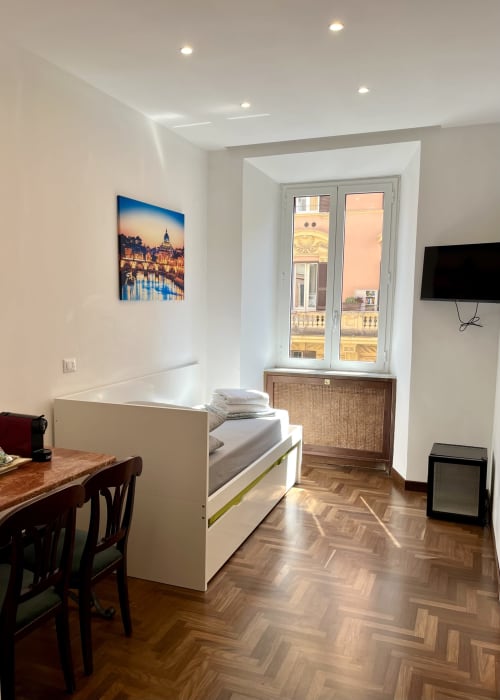 Camera moderna a Domus Giovanna Roma con letto matrimoniale, scrivania, TV a schermo piatto e vista sulla città dalle porte-finestre
