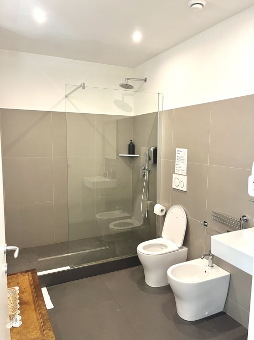 Bagno moderno a Domus Giovanna Roma con doccia walk-in, wc, bidet e lavabo con vanity bianco