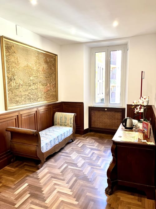 Camera da letto in stile classico romano con mobili in legno, pavimento in parquet, quadri incorniciati e finestre con vista sulla città presso Domus Giovanna